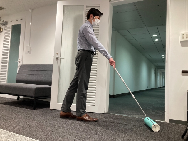 会社のカーペットにコロコロをかける男性