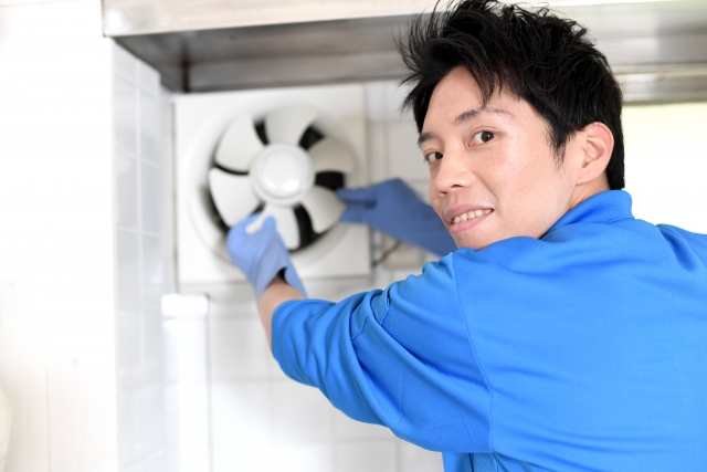 プロペラ式換気扇を清掃する作業員