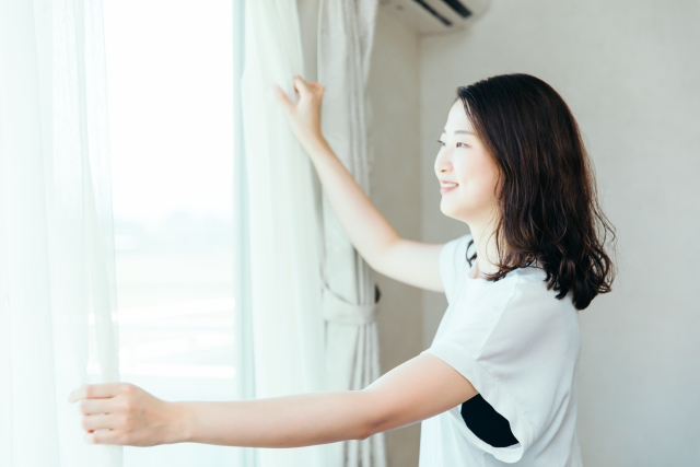 カーテンを開ける女性