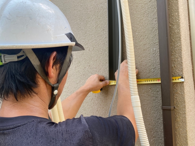 エアコン取付のために外壁を計測する人